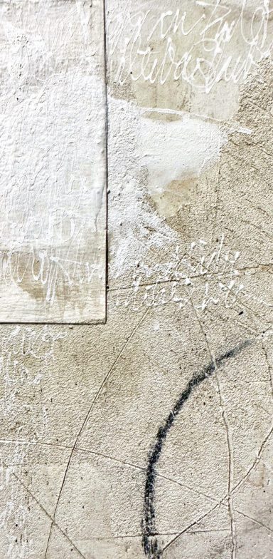 Texturierte, helle Oberfläche mit grauen und schwarzen Farbtönen und unregelmäßigen Mustern.